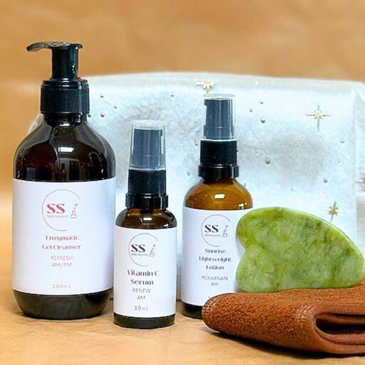 Set of skincare products including bottles and a green stone on a textured surface